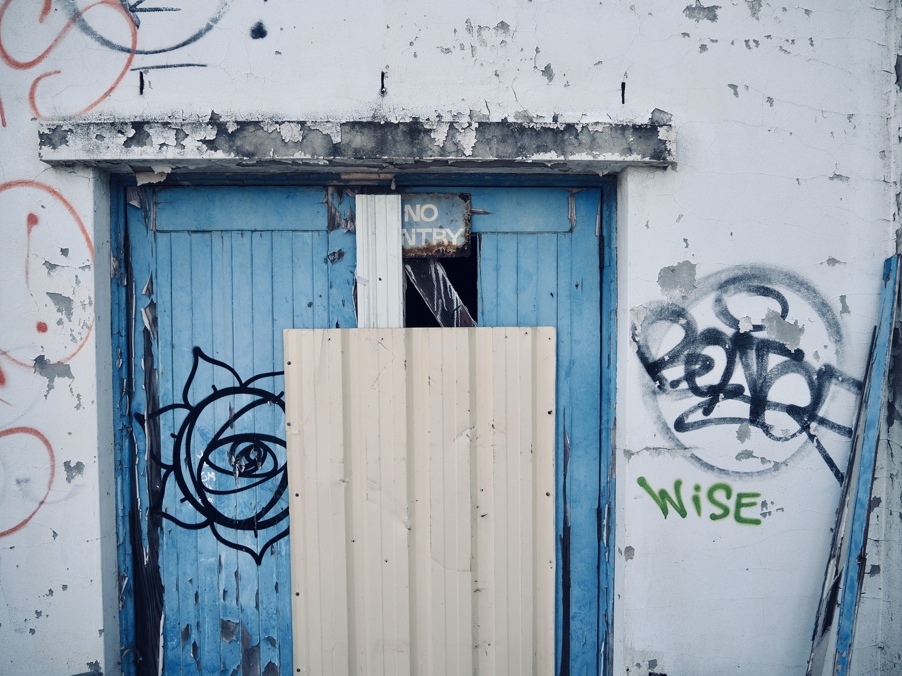 A boarded-up doorway with a sign that says 'No entry'
