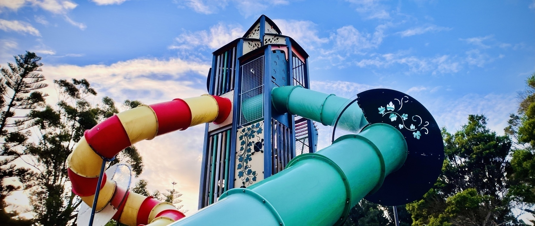 A widescreen shot of the top of a playground with winding slides