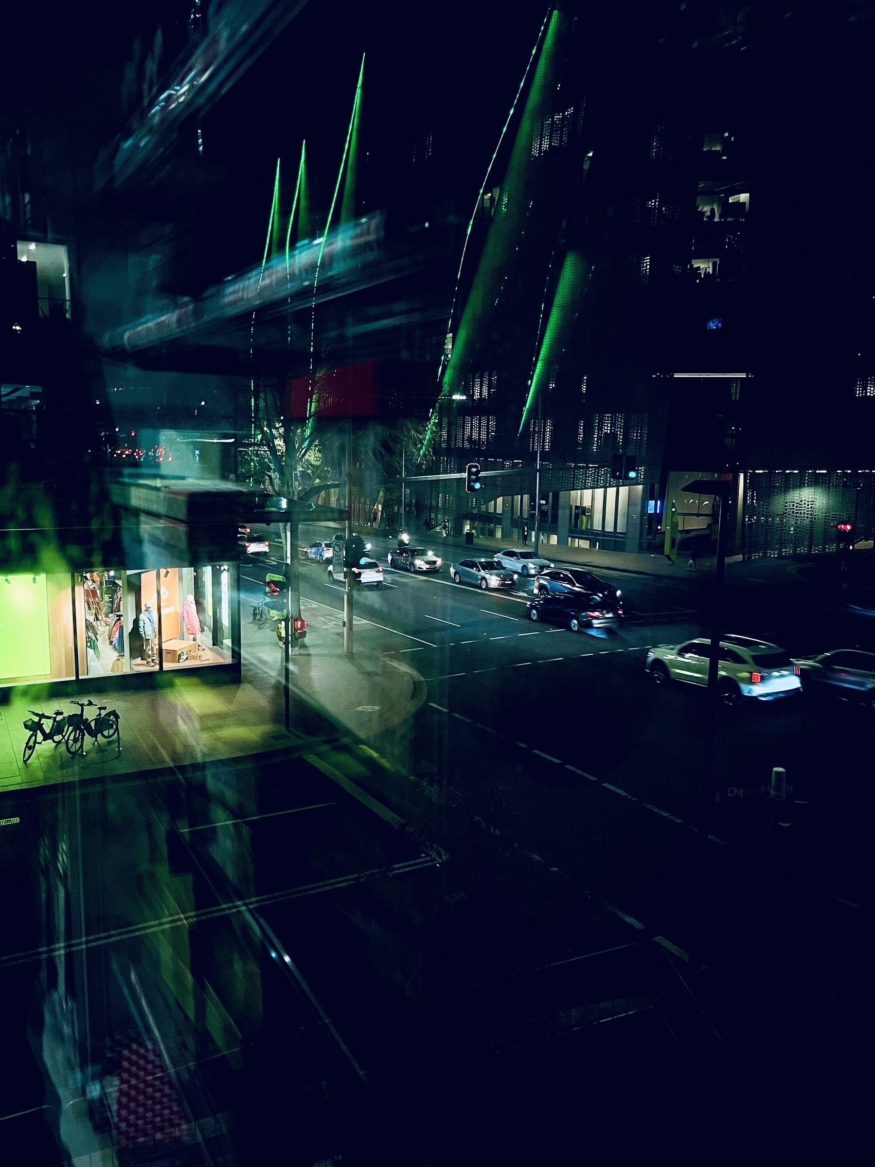 Overlooking a city intersection with green building lights and glass reflections