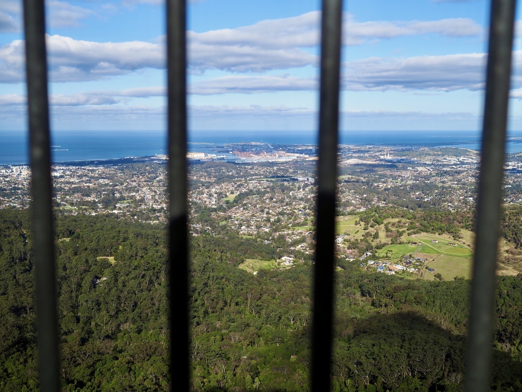 Looking over Port Kembla in the south of Wollongong through the bars of a lookout railing