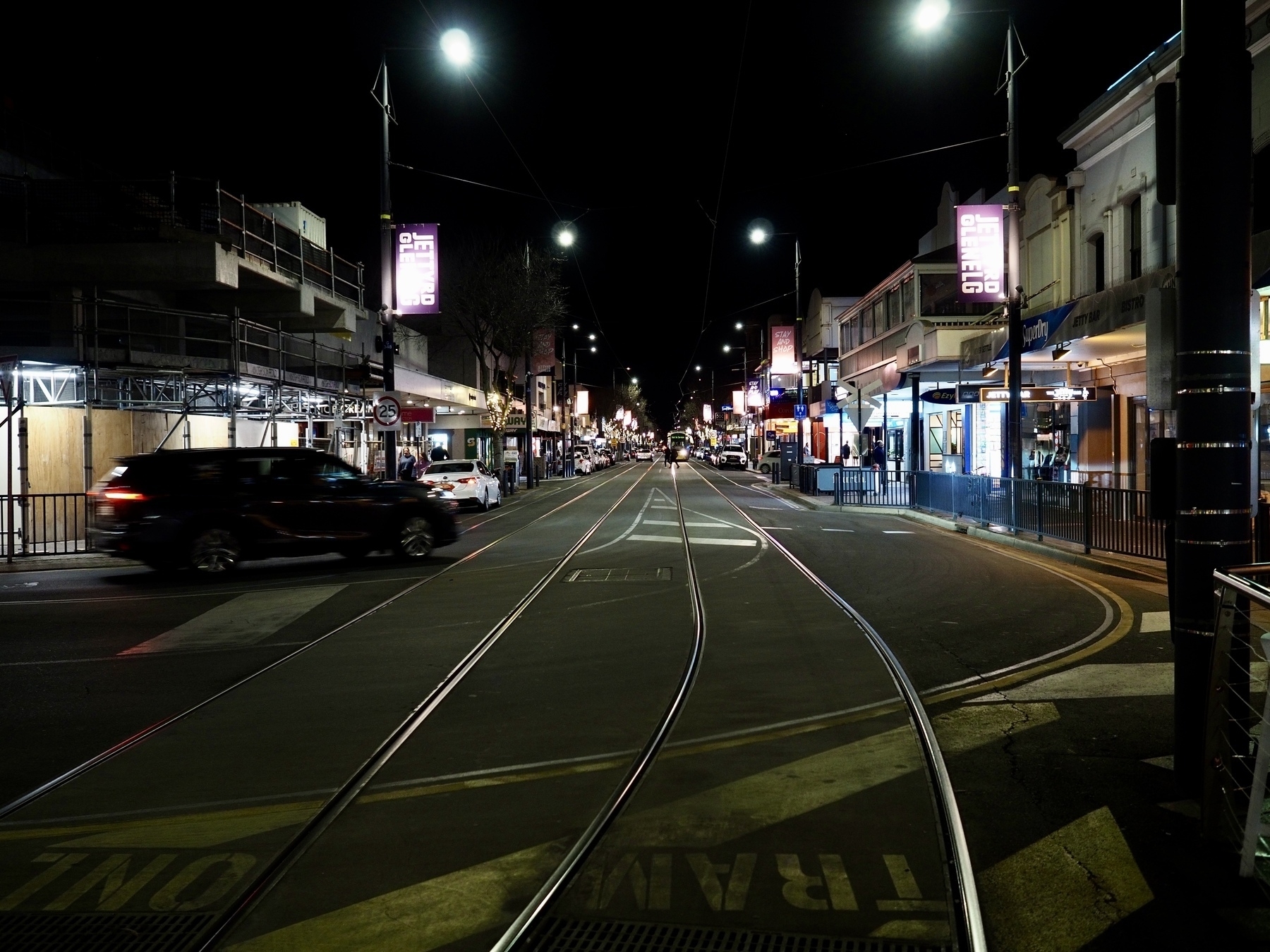 Looking down a street with tram lines at night