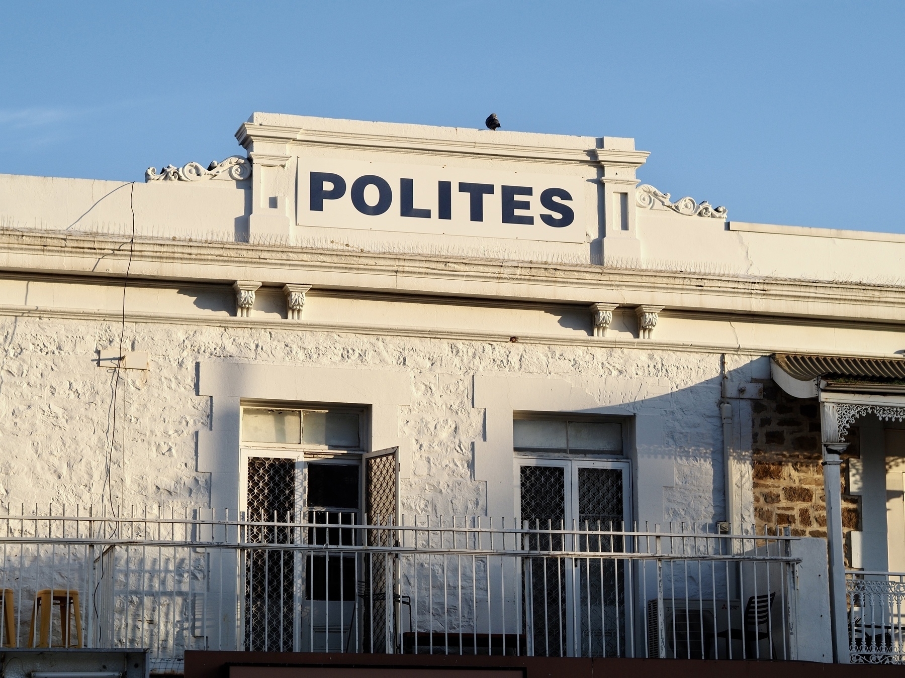A building that shows the name POLITES, with a pigeon on top
