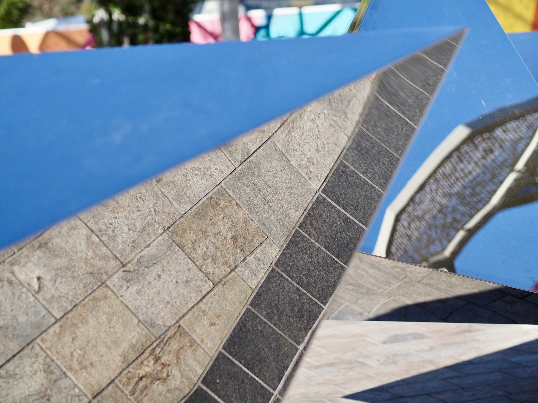 A reflective sculpture shows the pavers beneath itself.