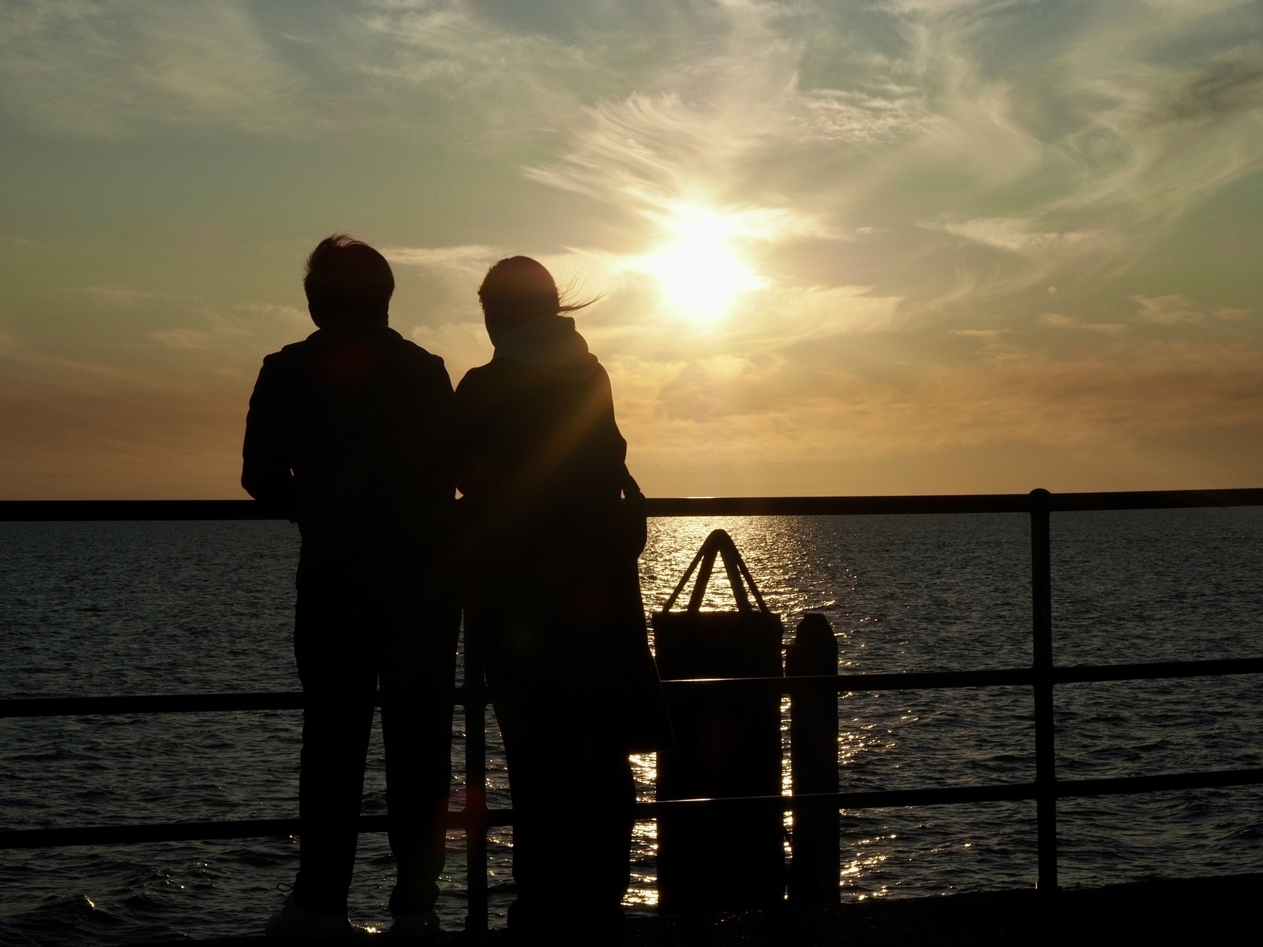 A couple enjoys sunset at the end of Glenelg Jetty.