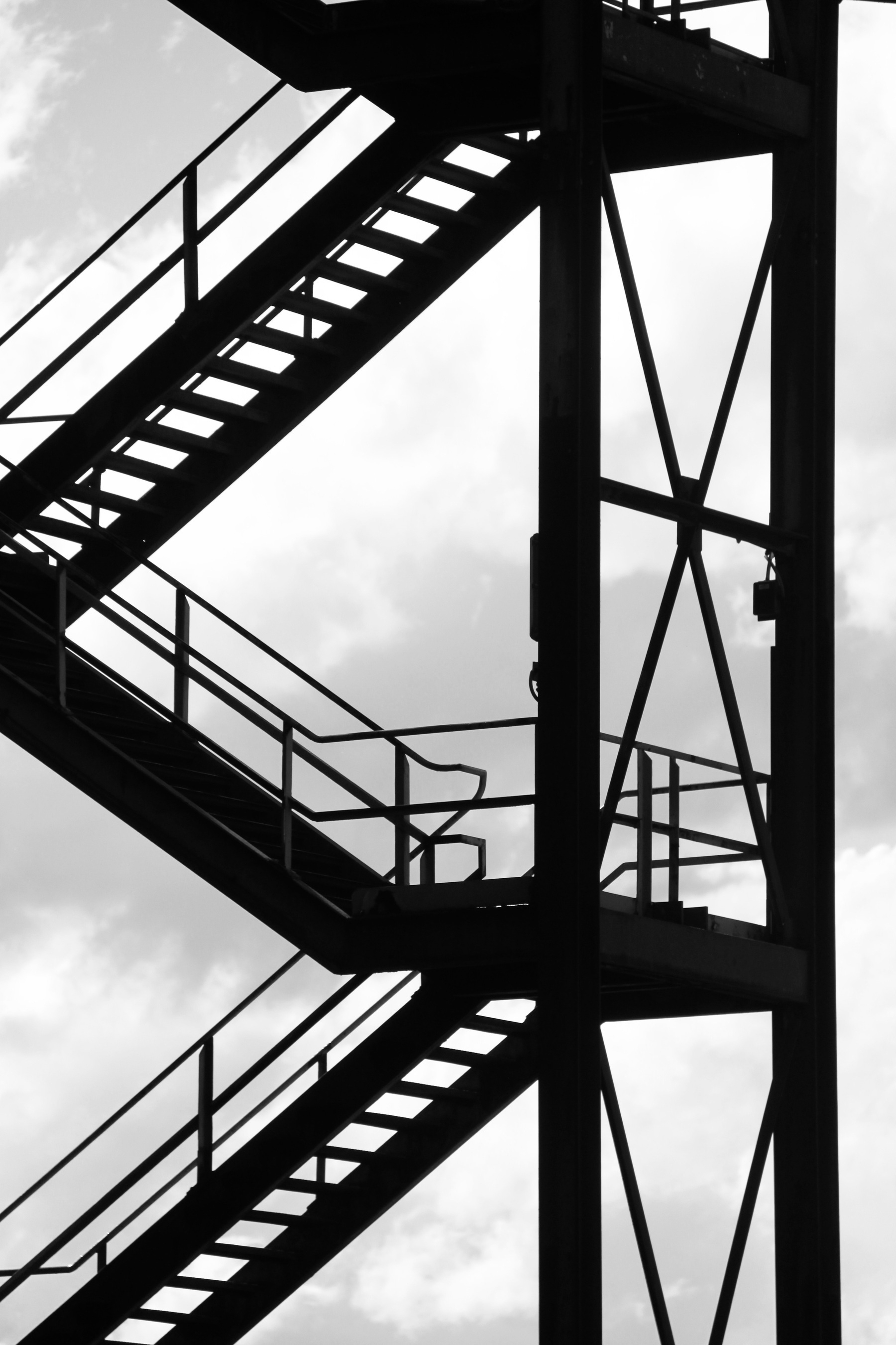 A black-and-white image of steel stairs with a cloudy backdrop