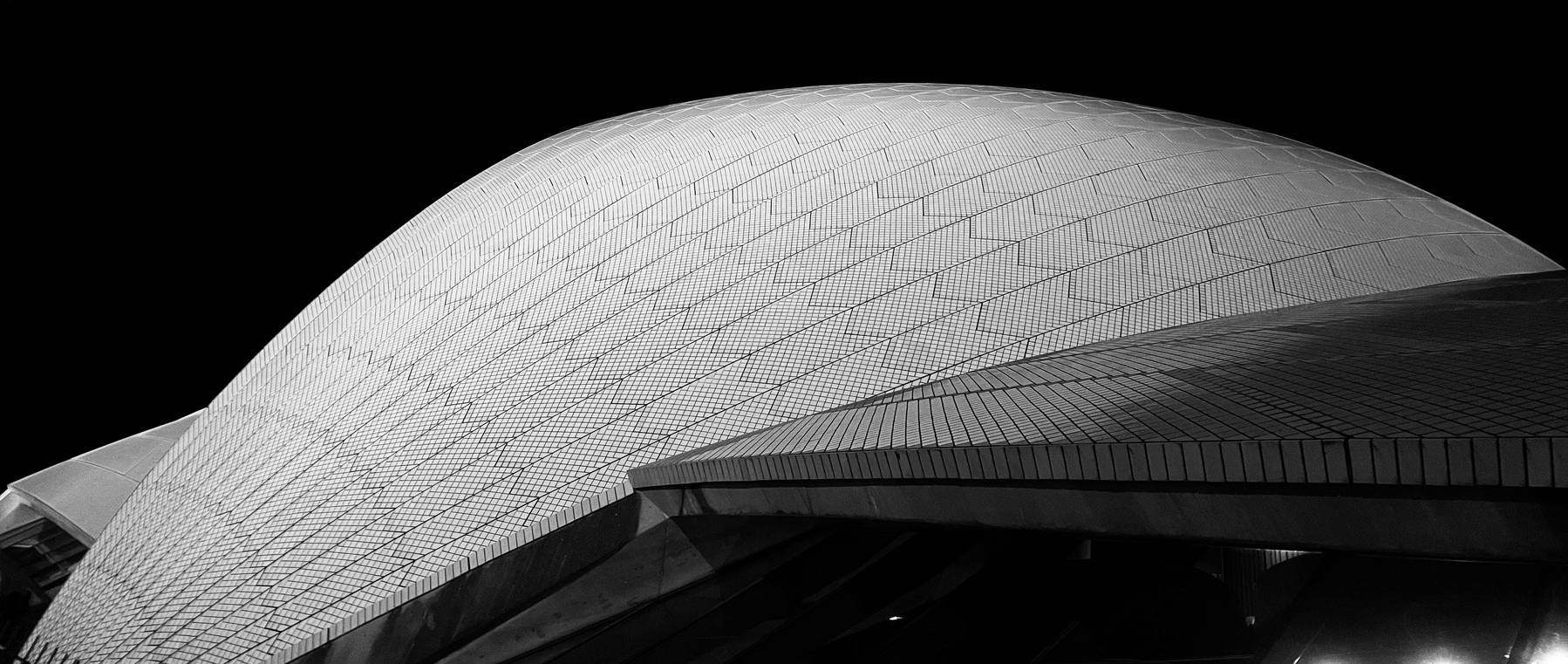 An anarmorphic black-and-white photo of the tiled roof of the Opera House